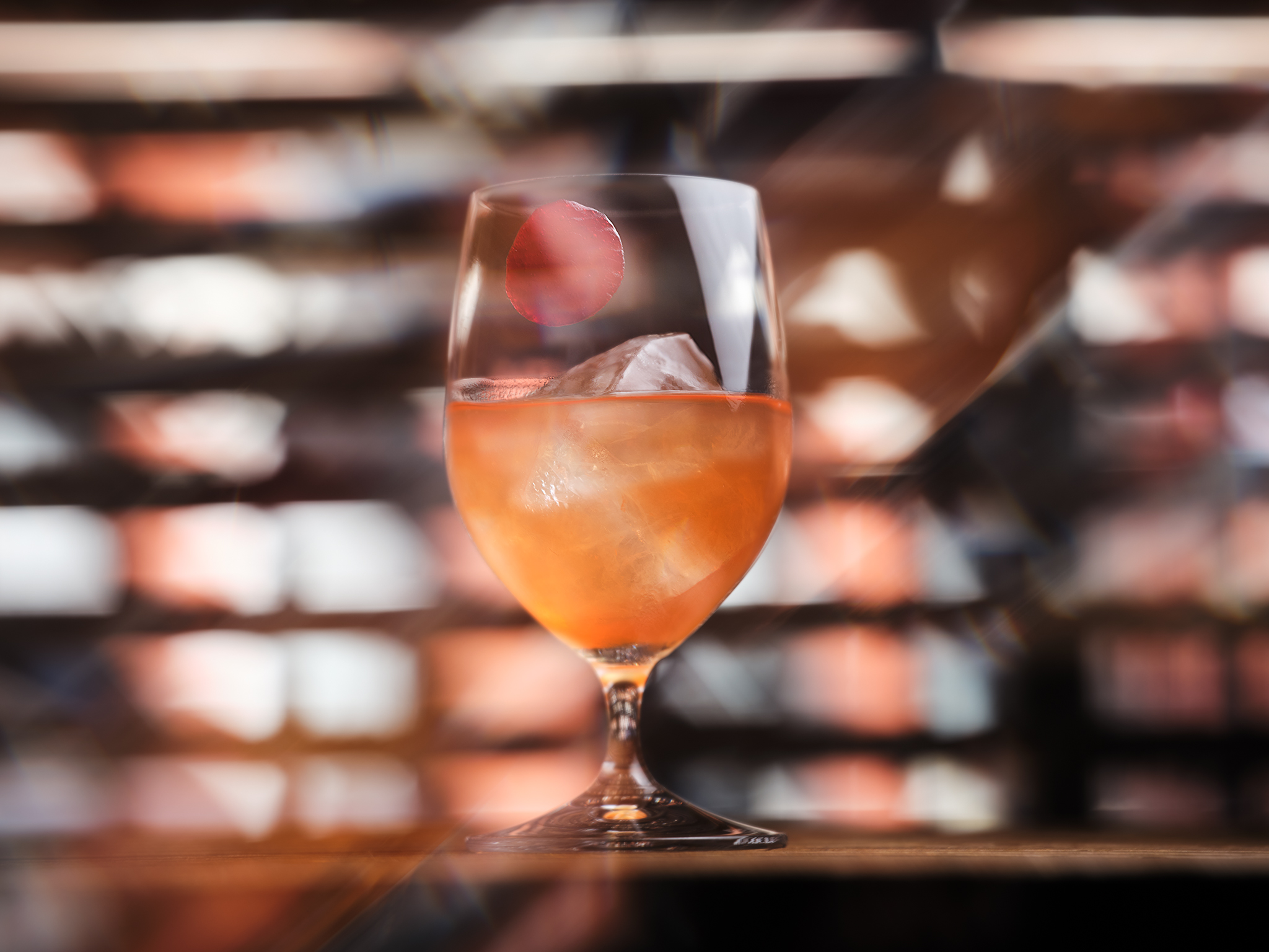 A pale orange cocktail in a short-stem wine glass
