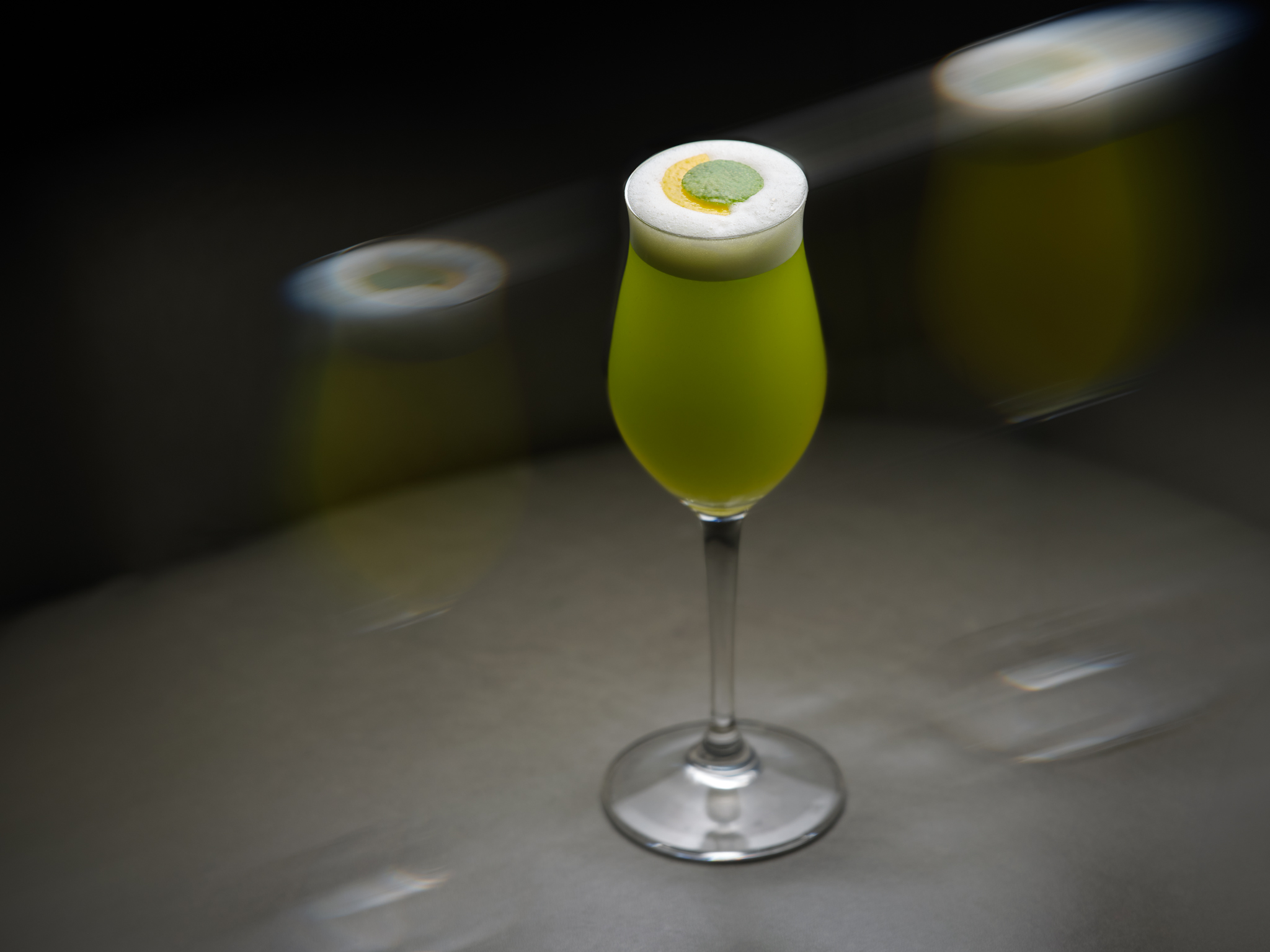 A green cocktail in a tulip champagne glass