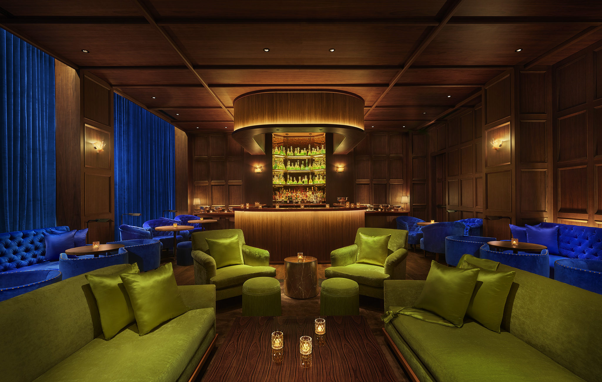 Dimly lit bar & lounge with bright blue and green velvet seating