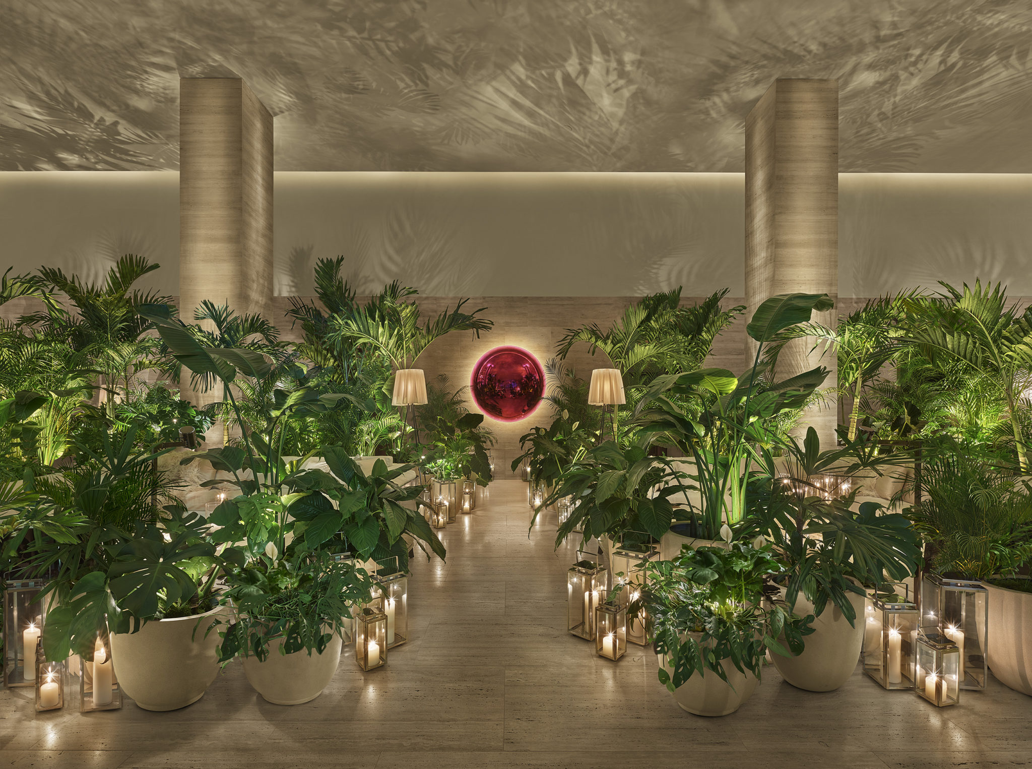 Lobby entrance lined with potted palms and glass encased candles