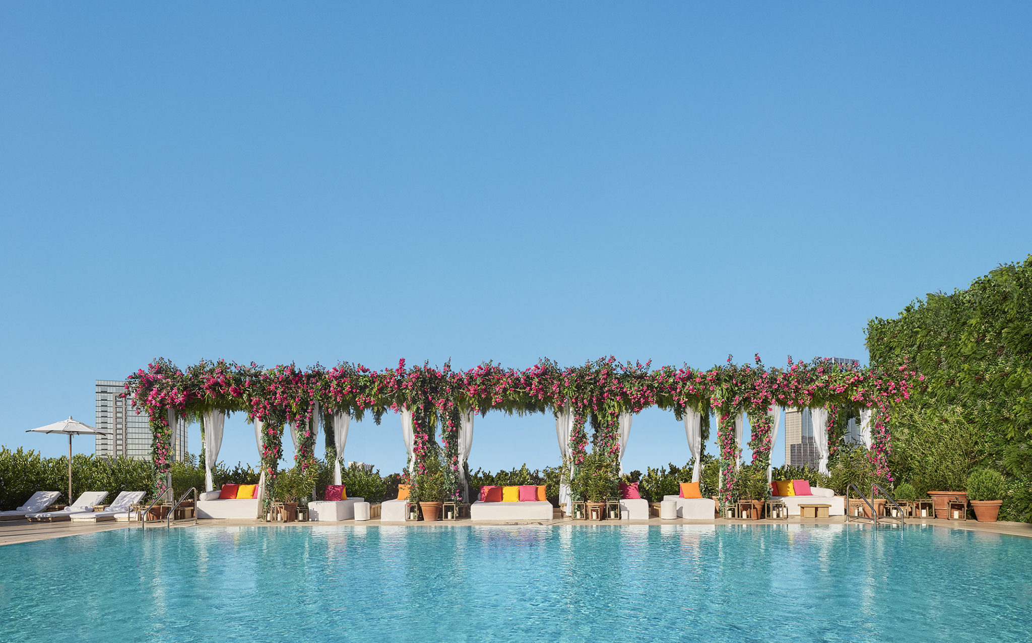 Sparkling pool lined with floral vine covered gazebo lounge space