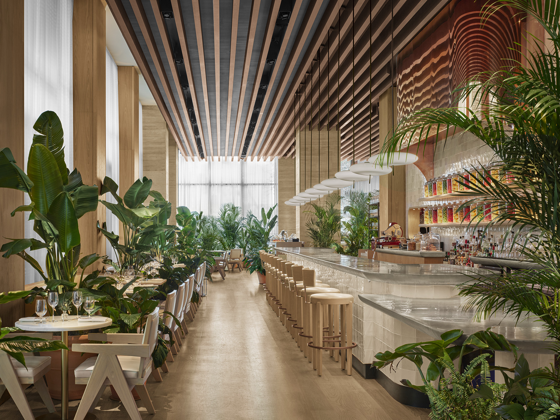 Dining area with tables and long bar decorated with tropical flora