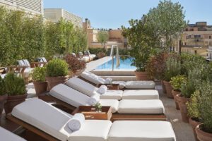 A view of outdoor lounge chairs surrounded by potted plants next to the pool.