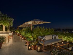 A nighttime view of outdoor couches surrounded by potted plants.