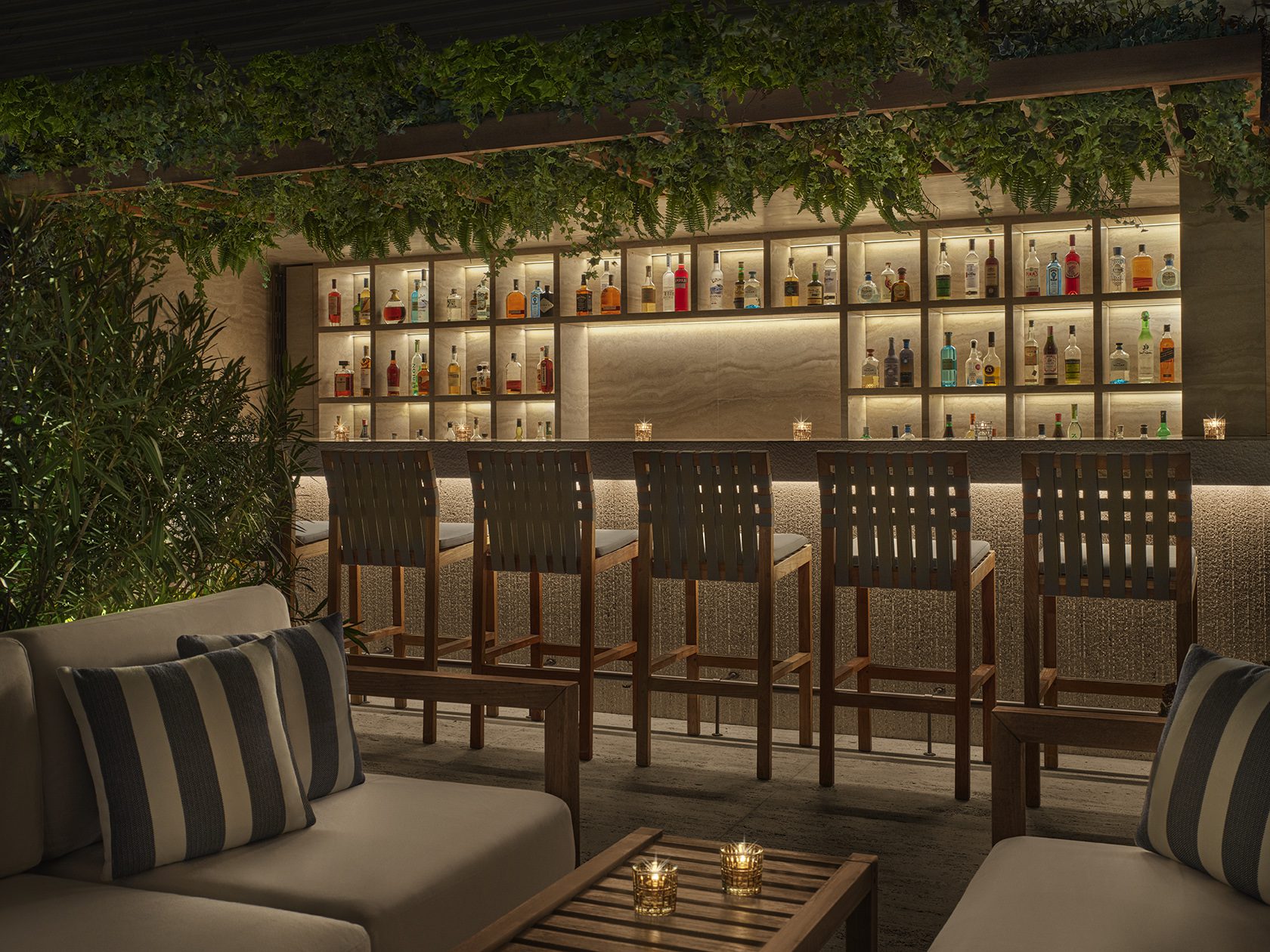 A dimly lit view of a bar with a grid of wall shelves filled with bottles.